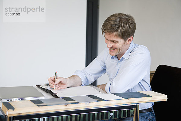 Lächelnder Geschäftsmann bei der Arbeit am Schreibtisch