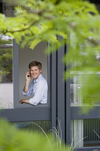 Geschäftsmann mit Handy im Fenster