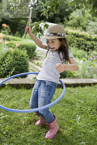 Mädchen spielt mit Hula Hoop im Hinterhof