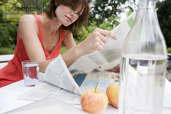 Frau liest Zeitung im Hinterhof