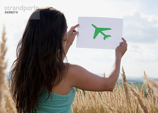 Frau hält Bild vom Flugzeug am Himmel