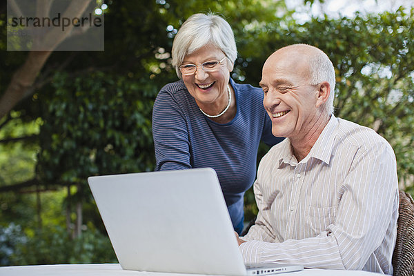 Älteres Paar mit Laptop im Freien