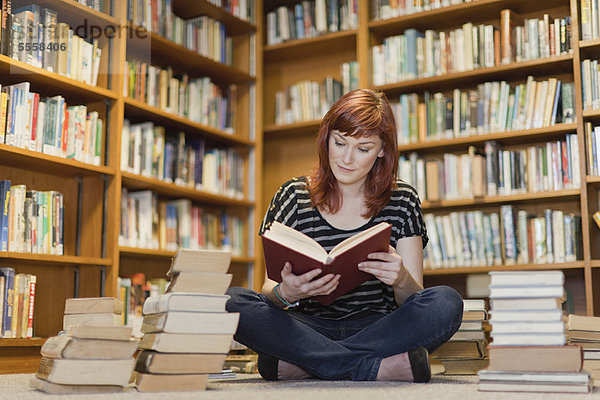 Student im Bücherstapel in der Bibliothek