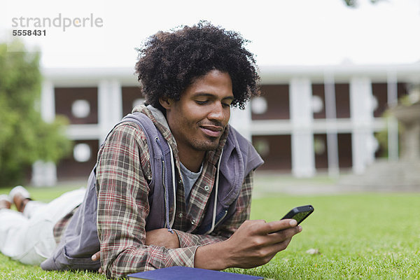 Student mit Handy auf Rasen