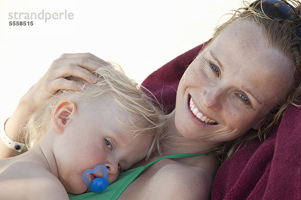 Frau lächeln Strand umarmen Baby