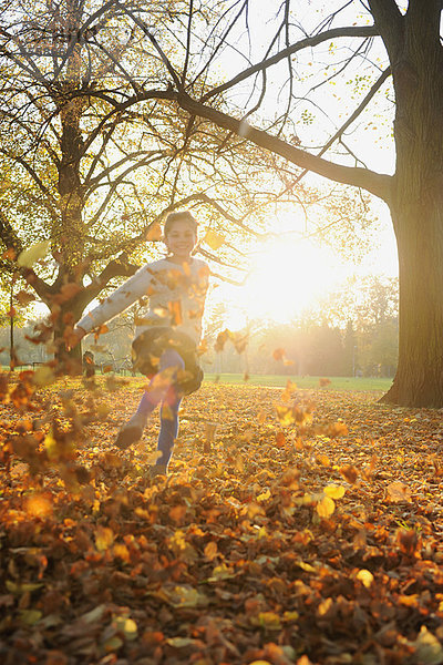 Lächelndes Mädchen spielt im Herbstlaub