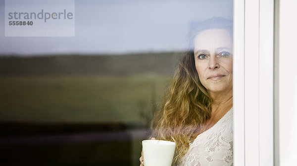 Frau bei einer Tasse Kaffee am Fenster