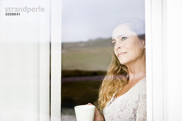 Frau bei einer Tasse Kaffee am Fenster