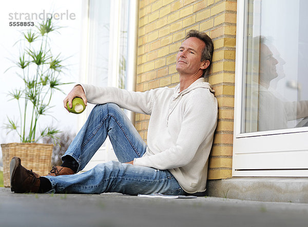 Mann isst Apfel auf der Veranda