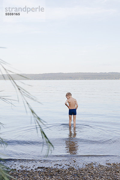 Junge waten am felsigen Strand