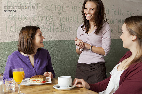 Frauen im Gespräch mit Kellnerin im Café