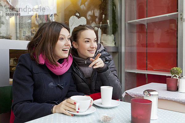 Lächelnde Frauen beim Kaffee im Freien