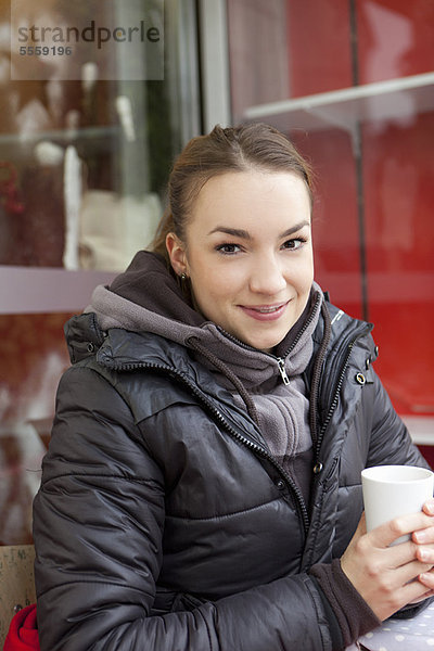 Lächelnde Frau beim Kaffee im Freien