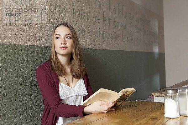 Frau liest Buch im Café