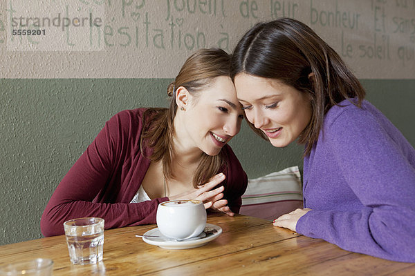 Frauen flüstern sich im Café zu.