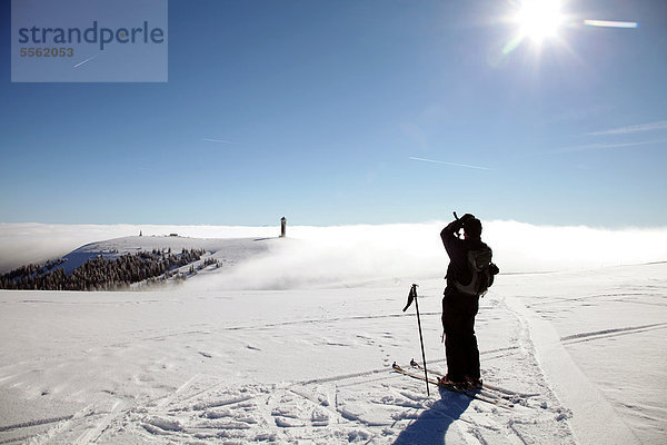 Ein Skiwanderer genießt die Aussicht vom Gipfel des Feldbergs zum Seebuck im Nebel  Schwarzwald  Baden-Württemberg  Deutschland  Europa  ÖffentlicherGrund