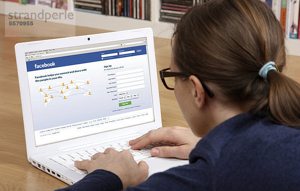 Frau am Laptop surft im Internet  englische Facebook Seite