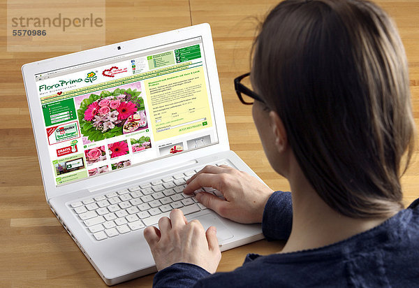 Frau am Laptop surft im Internet  Onlineshop für Blumen