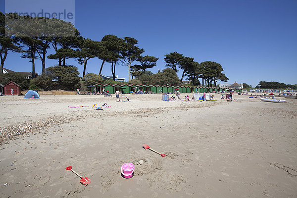 Verlassenes Spielzeugeimerchen und Schippen am Strand von Mudeford mit Kiefern und Strandhütten  Mudeford  Dorset  England  Großbritannien  Europa