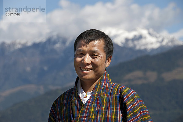 Mann lächelt  Portrait  traditionelle Kleidung Gho  karierter Stoff  Himalaja  Königreich Bhutan  Südasien  Asien