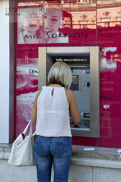 Frau an einem Geldautomat an einer Filiale der portugiesischen Bank Millenium BCP  Banco Comercial Portugues  Portugiesische Handelsbank  in Lissabon  Portugal  Europa