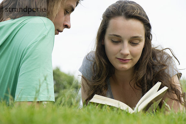 Junges Paar beim gemeinsamen Lesen im Freien