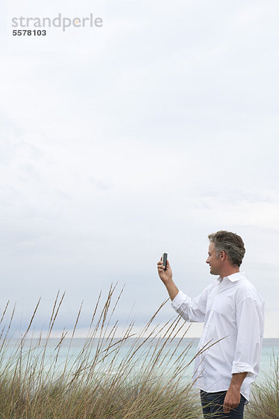 Erwachsener Mann fotografiert Szenerie mit Handy