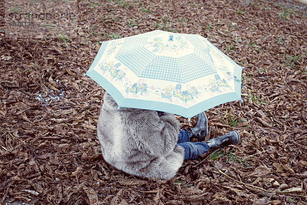 Kind unter Schirm sitzend