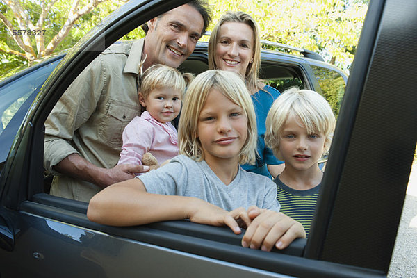 Familie posiert neben dem Auto  Blick durch offenes Fenster  Porträt