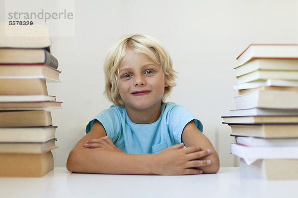 Junge sitzt zwischen zwei Stapeln von Büchern  Porträt