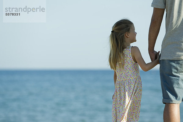 Mädchen mit der Hand ihres Vaters am Strand  abgeschnitten
