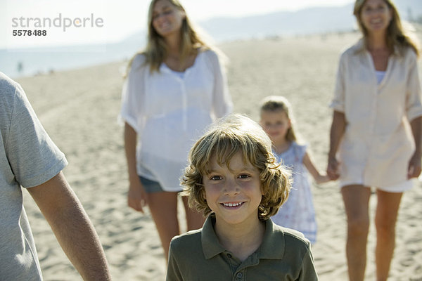 Junge  der mit seiner Familie am Strand spazieren geht.