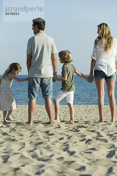 Familie hält sich am Strand an den Händen