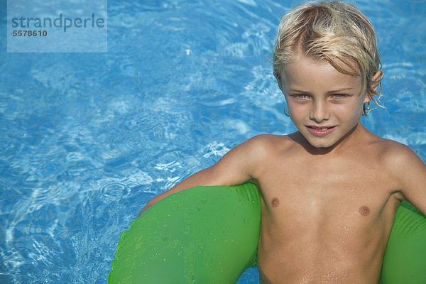 Junge entspannt auf dem Floß im Pool