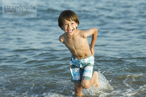 Junge spielt im Wasser am Strand