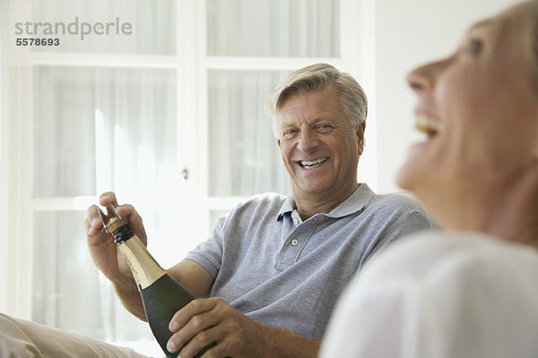 Paar entspannt zusammen  Mann öffnet Flasche Champagner