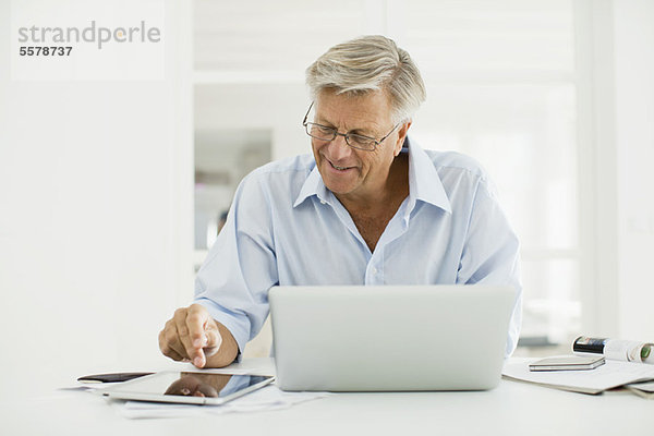 Senior Mann mit digitalem Tablett und Laptop Computer