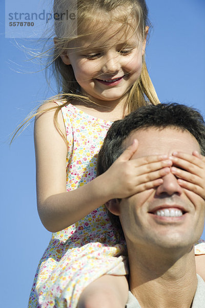 Mädchen  das Vaters Augen mit ihren Händen bedeckt.