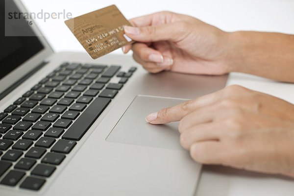 Frau mit Kreditkarte bei der Benutzung des Laptops  beschnitten