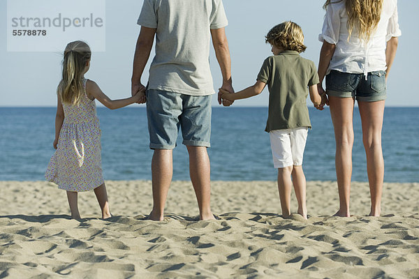 Familie beim Händchenhalten am Strand  Rückansicht