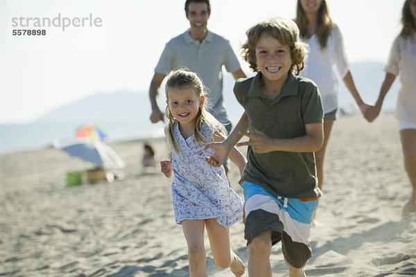 Kinder laufen am Strand  Familie im Hintergrund