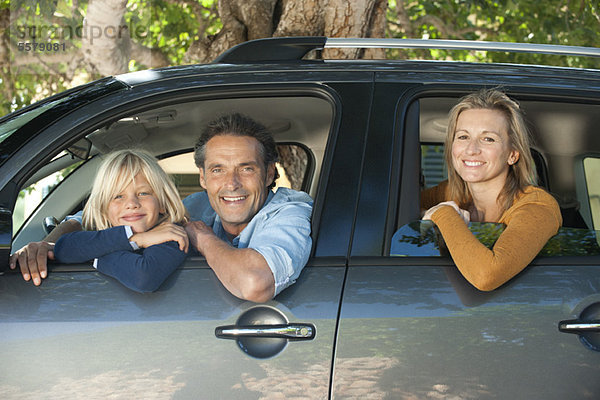 Familie zusammen im Auto  aus den Fenstern lehnend und lächelnd vor der Kamera