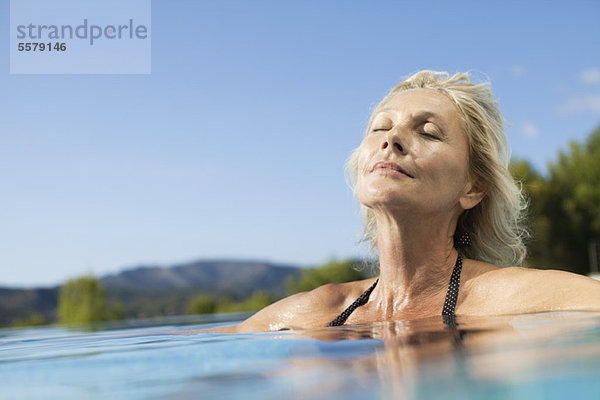 Reife Frau entspannt im Pool mit geschlossenen Augen