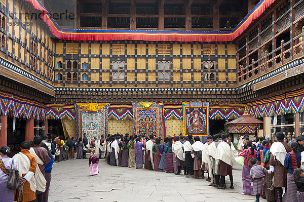 Tibetischer Buddhismus  Festival  Menschen in Gho Tracht stehen in einer Schlange an  Klosterfestung Rinpung Dzong  Innenhof  Paro  Himalaja  Königreich Bhutan  Südasien  Asien