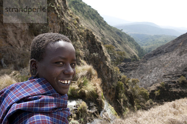 Ethnologie  Portrait  lächelnder Junge der Massai  Maasai  Schlucht am Olmoti-Krater  bei Nainokanoka  Ngorongoro Conservation Area  Tansania  Ostafrika  Afrika