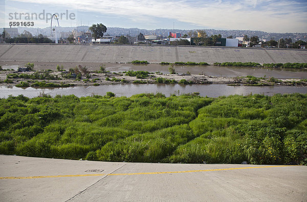 Der verschmutzte Tijuana River wie er die Vereinigten Staaten von Mexiko her erreicht  die gelbe Linie im Vordergrund ist die Grenze zwischen den Vereinigten Staaten und Mexico  San Ysidro  Kalifornien  USA