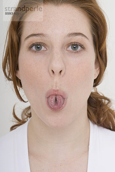 Junge Frau mit ausgestreckter Zunge  Porträt