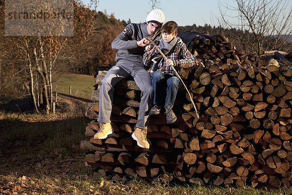 Deutschland  Bayern  Vater und Sohn sitzen auf Holz und Schneidstock