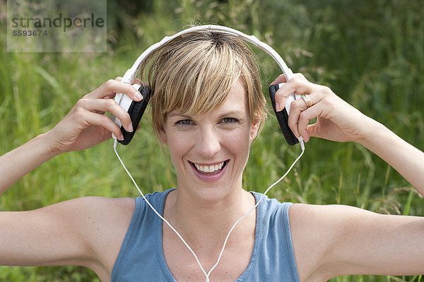 Mittlere erwachsene Frau  die Musik hört  lächelnd  Portrait
