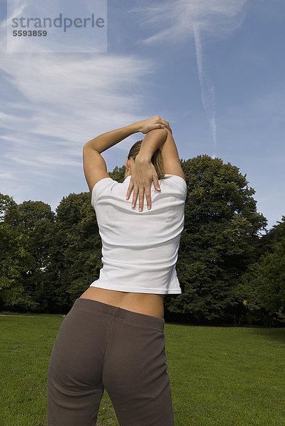 Deutschland  Nordrhein-Westfalen  Düsseldorf  Junge Frau beim Stretching im Park